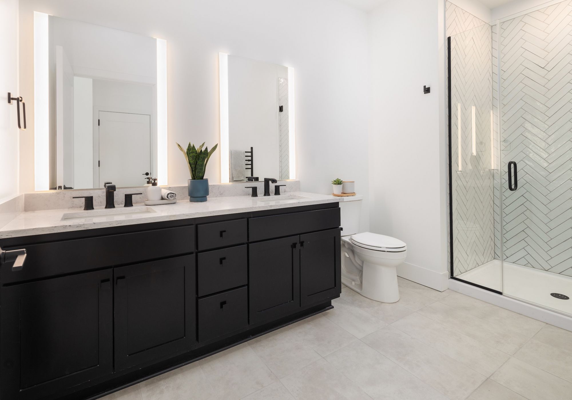 Moment apartments penthouse bathroom with porcelain tile, glass shower, double vanities, and quartz countertops