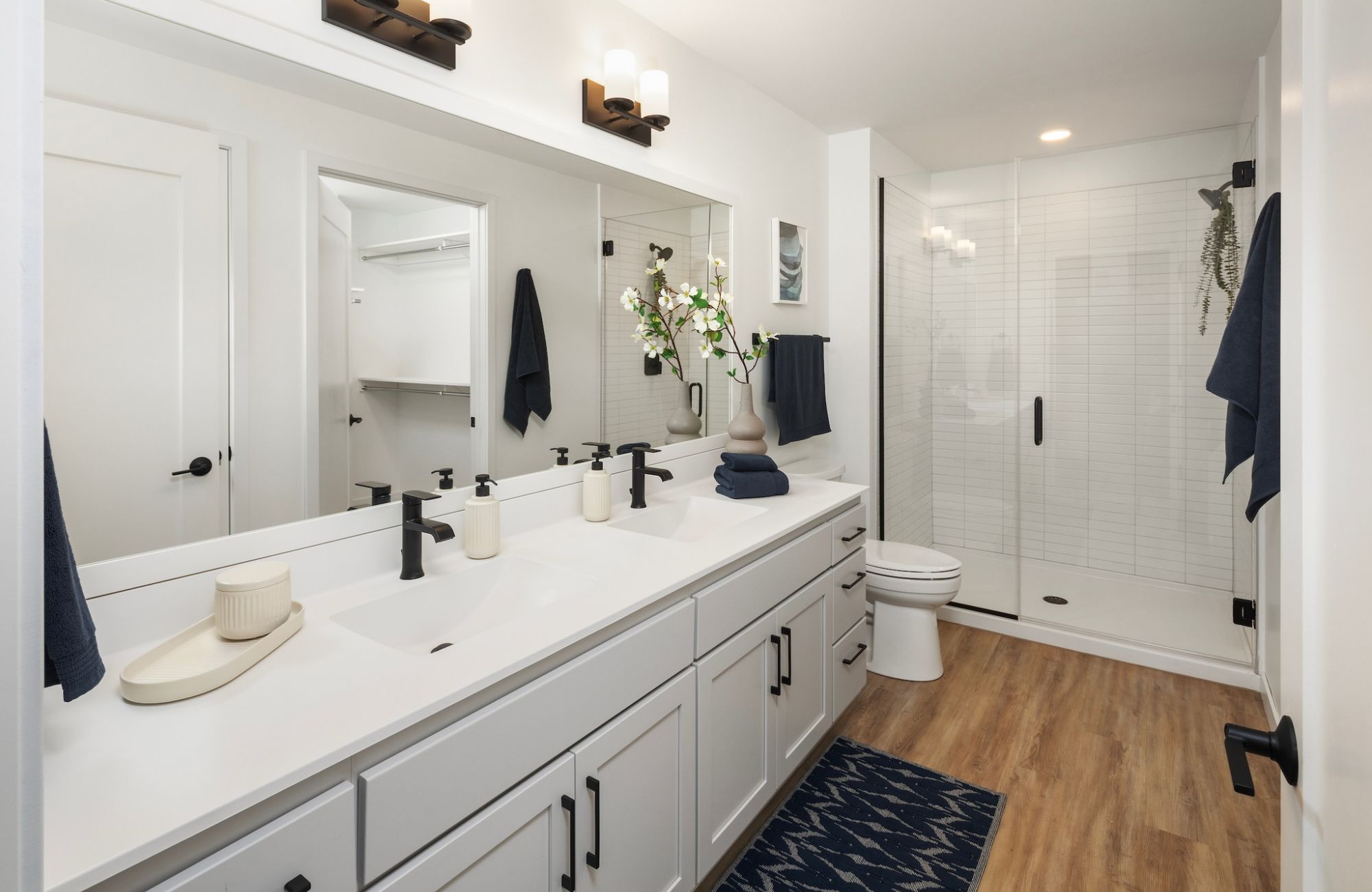 Moment apartments bathroom with beautiful white countertops, double sinks, and glass enclosed shower