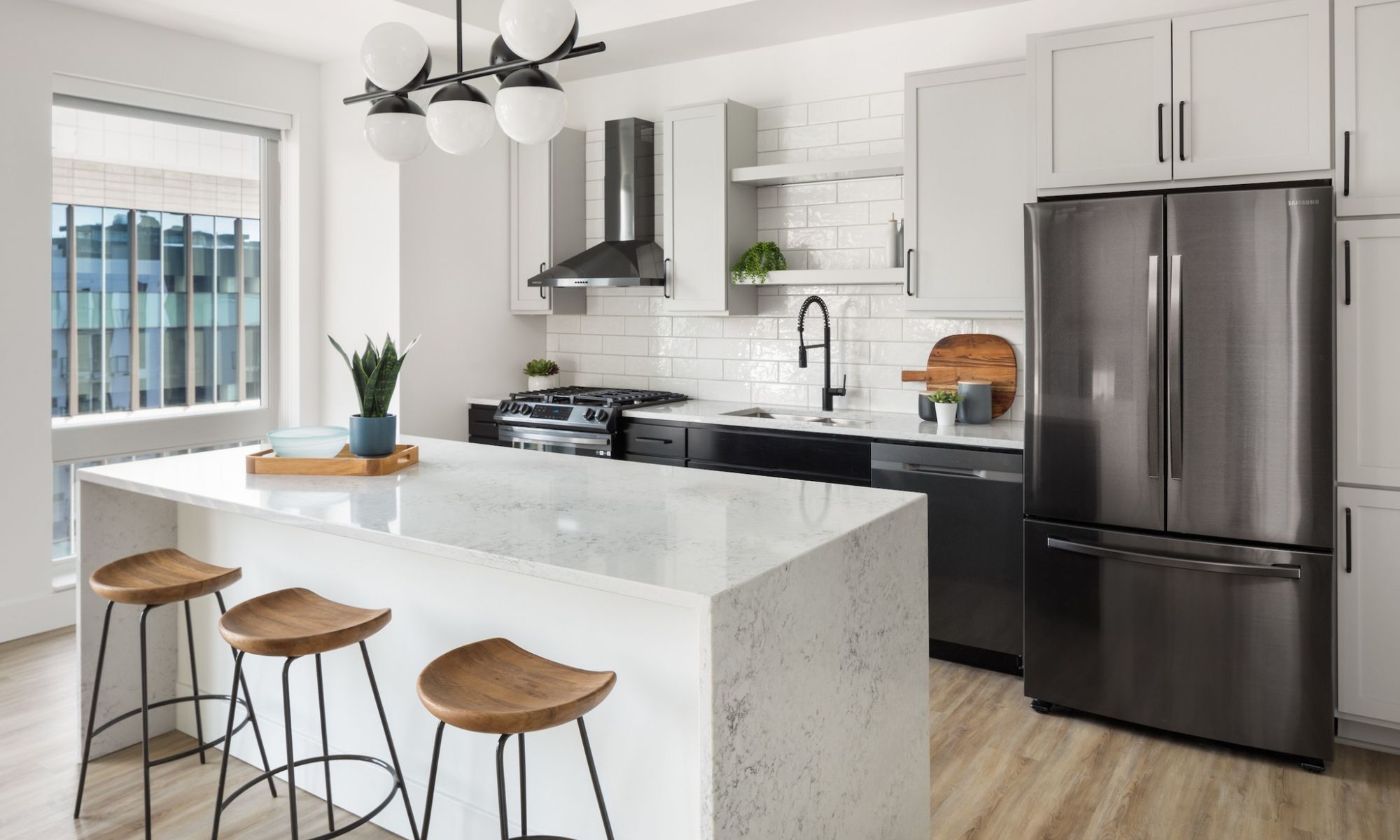 Moment apartments penthouse kitchen with high-end appliances, tile backsplash, and waterfall kitchen island